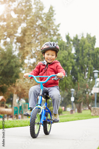Fototapeta Naklejka Na Ścianę i Meble -  Young Boy Riding Bike In Park