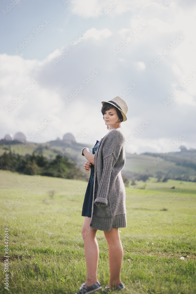Young pretty woman in a straw hat posing on a green meadow Young pretty woman in a straw hat posing on a green meadow