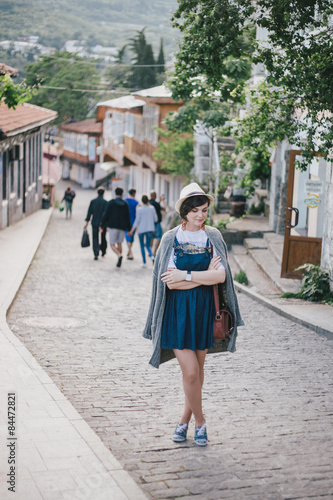 Young fashion woman in a straw hat and over sized knitted sweater posing in a city center