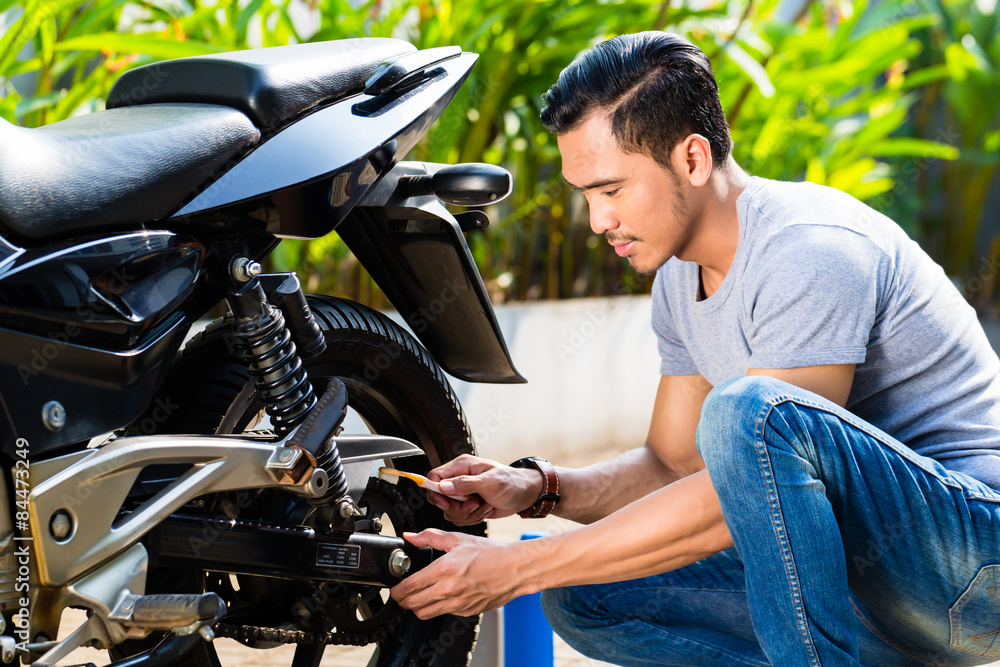 Naklejka premium Asian man at motorcycle maintenance