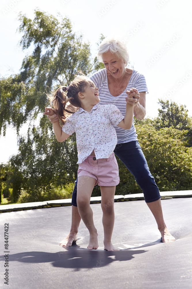 Grandmother And Granddaughter Bouncing On Trampoline Grandmother And Granddaughter Bouncing On Trampoline