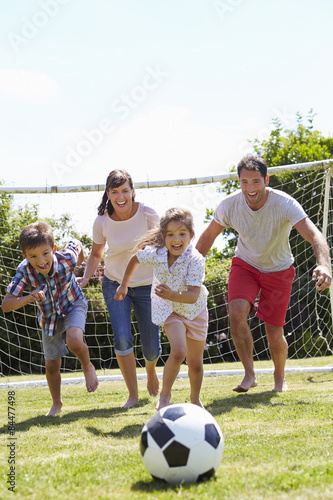 Family Playing Football In Garden Together