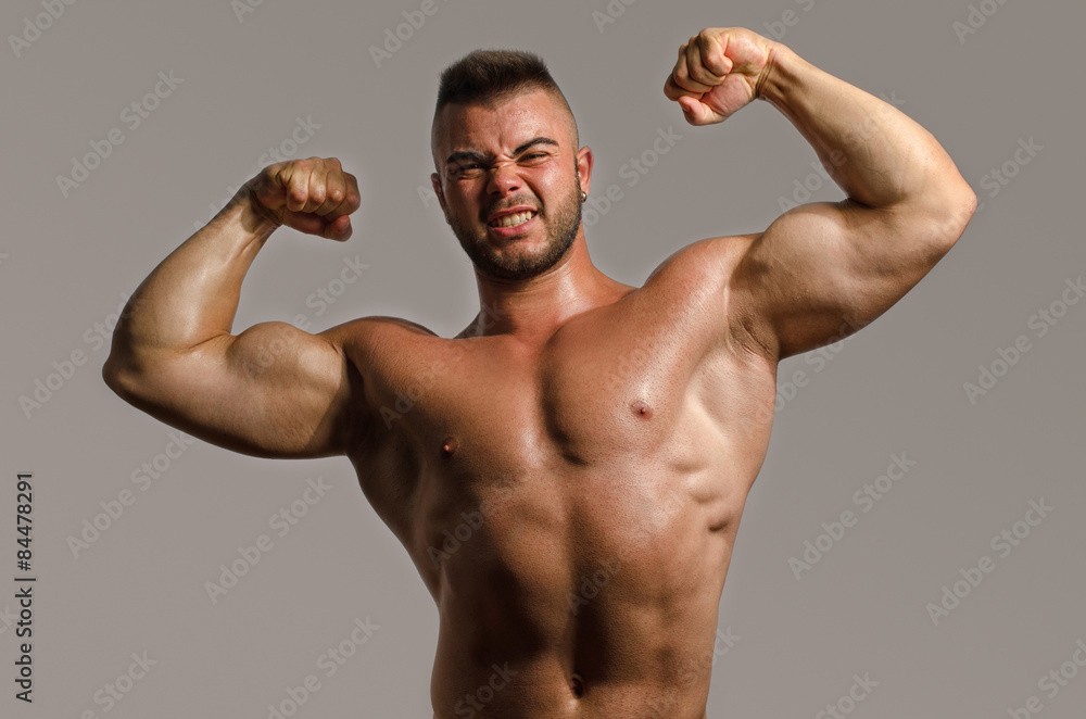 Bodybuilder topless, flexing his big biceps. Strong man with