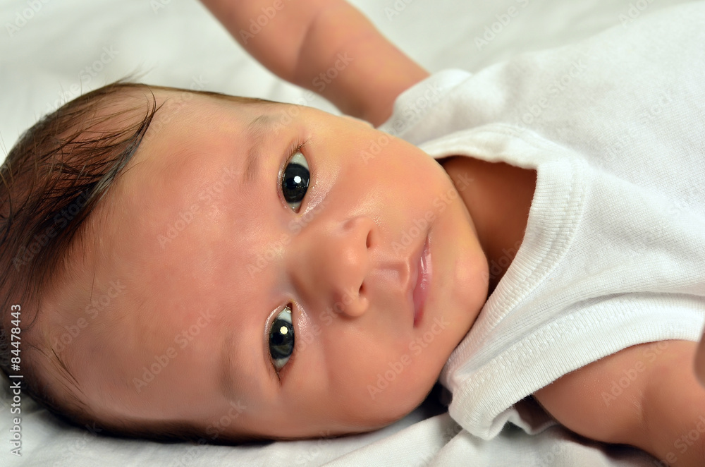 Portrait of a newborn, cute baby looking at you. Adorable little boy relaxing in white sheets after a bath Portrait of a newborn, cute baby looking at you. Adorable little boy relaxing in white sheets after a bath