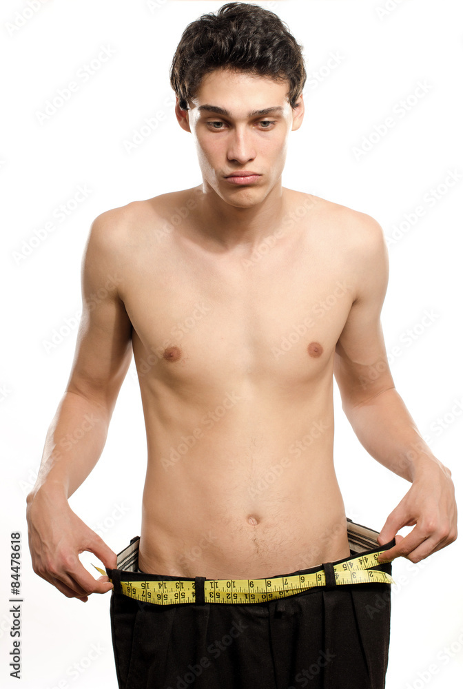 Skinny young man with large pants,anorexic look, slim body. Man lost weight  and comparing his larger pants from the days he was fat. Before and after,  fat or slim Stock Photo