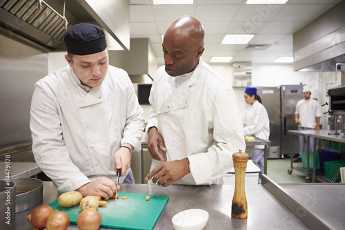 Teacher Helping Students Training To Work In Catering