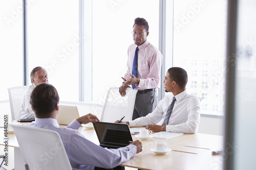 Four Businessmen Having Meeting Around Boardroom Table