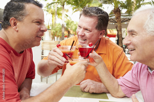 Senior Male Friends Enjoying Cocktails In Bar Together