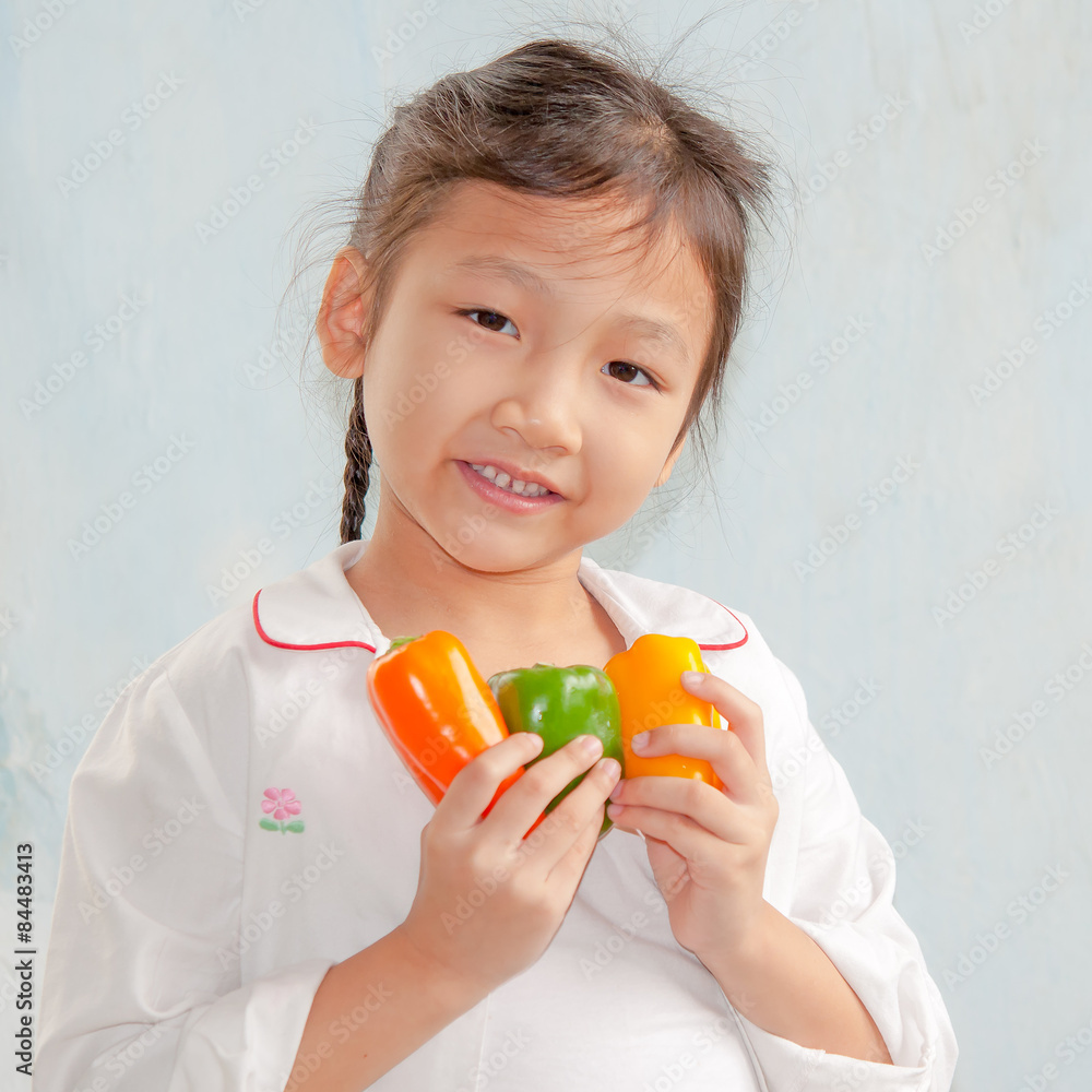 little girl holding capsicum in kitchen little girl holding capsicum in kitchen