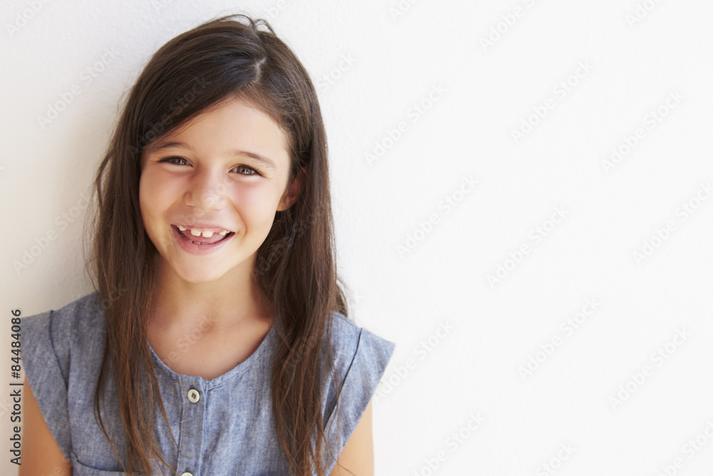 Smiling Young Girl Standing Outdoors Against White Wall Smiling Young Girl Standing Outdoors Against White Wall