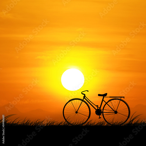 The silhouette of the bike and orange sky at sunset. © noppadon