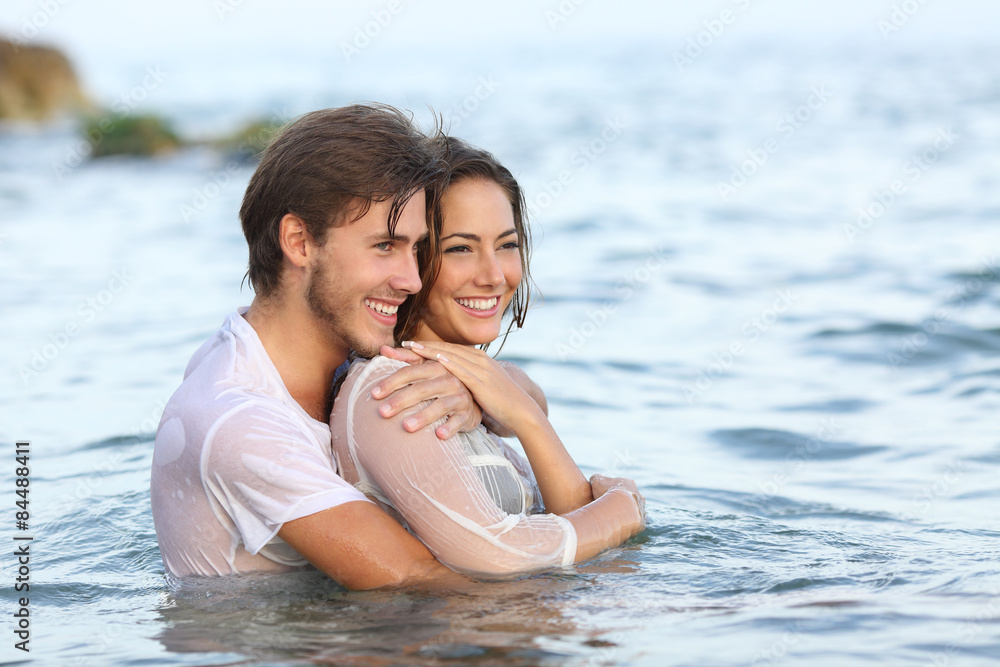Fototapeta premium Happy couple in love hugging and bathing in the beach