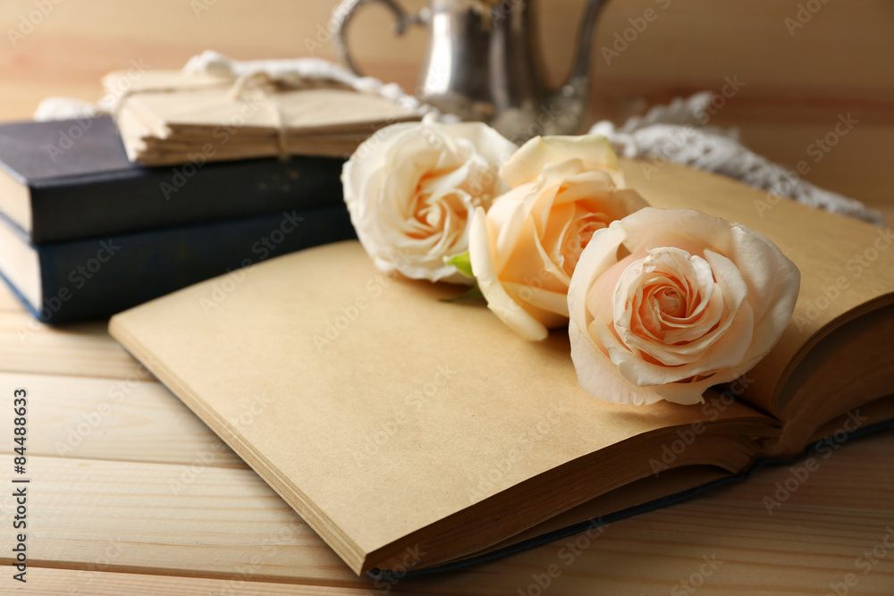 Fresh roses on old notebook, on wooden table background Fresh roses on old notebook, on wooden table background