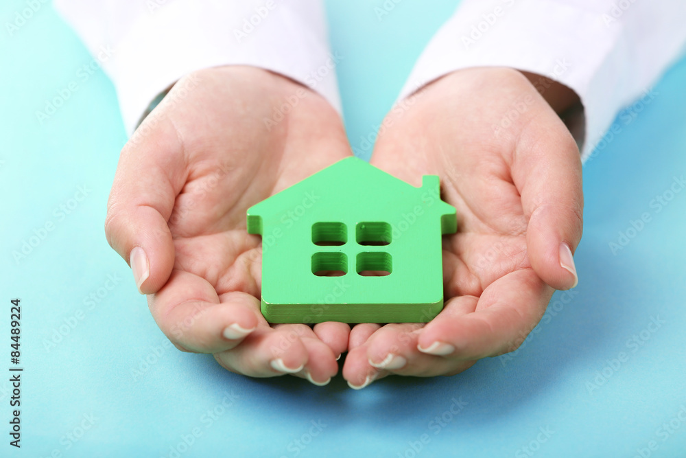 Female hands holding house on color background Female hands holding house on color background