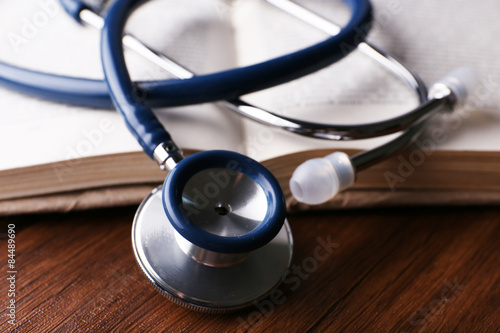 Stethoscope on book on wooden table  closeup