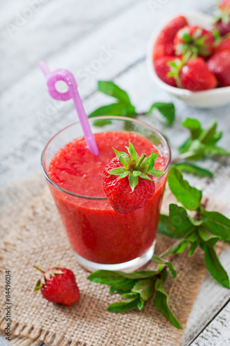 Strawberry smoothie in glass and mint leaves in rustic style