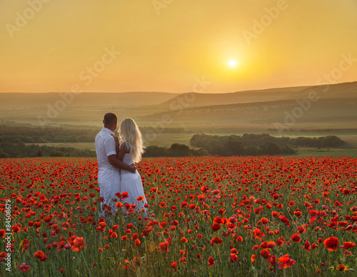 Loving couple hug one another during romantic date in poppy field photo