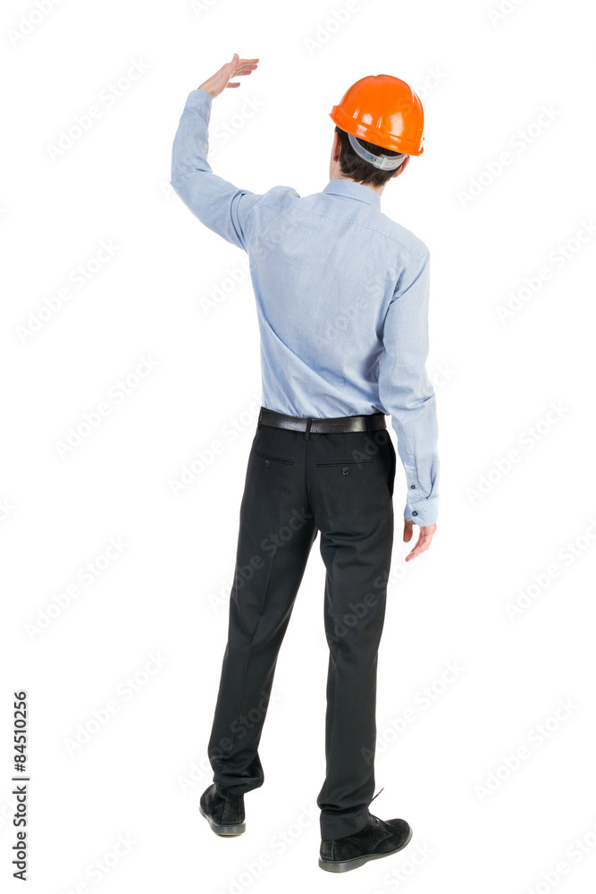 Backview of an engineer in construction helmet stands. Standing Backview of an engineer in construction helmet stands. Standing