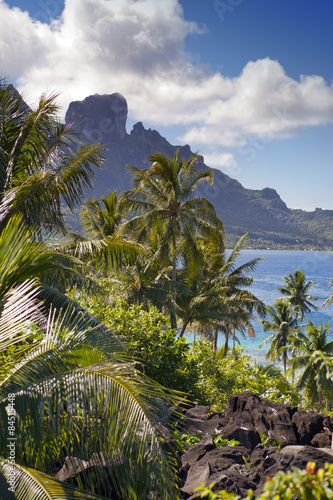 View of the Otemanu mountain through the palms and ocean. Bora-Bora. Polynesia