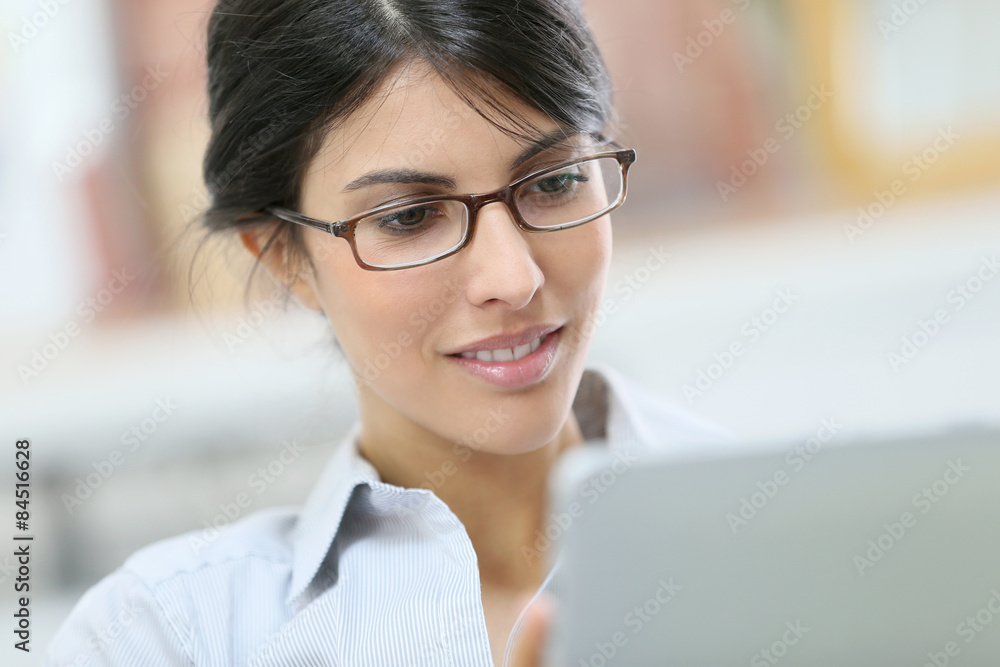 Young woman with eyeglasses using digital tablet