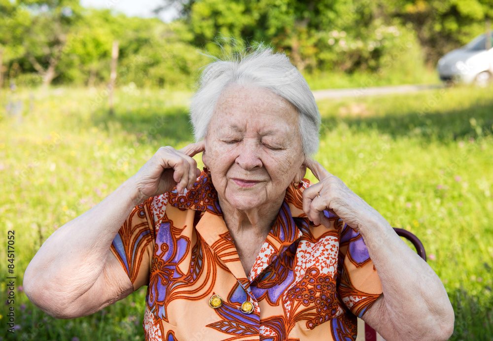 Old woman covers her ears with hands