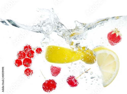 Fresh fruits and berries splashing in water isolated on white