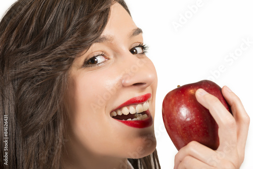 Beautiful young woman eating an red apple, studio shot on white
