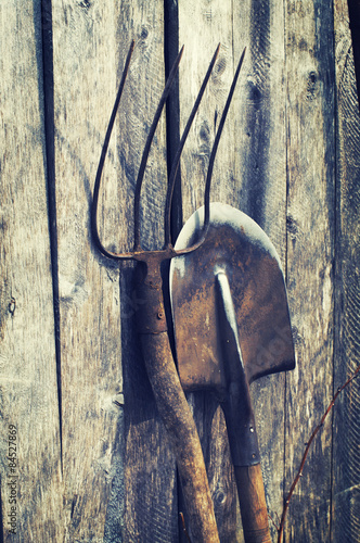 Valokuva Shovel and pitchfork on a wooden background. Old garden tools.