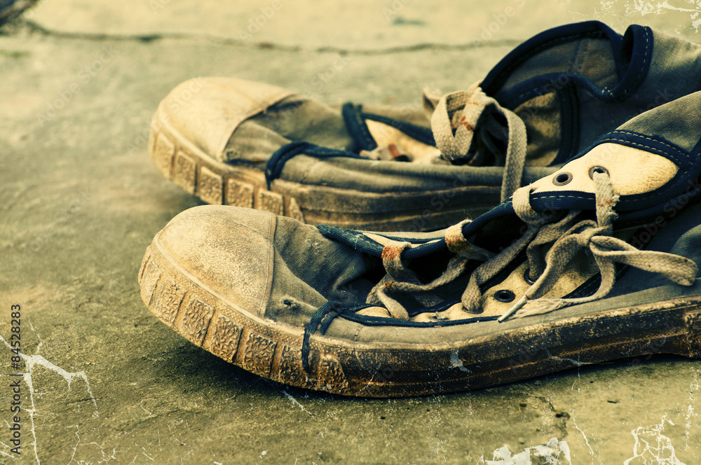Old dirty retro gym shoes on grunge a background. Old sports shoes. Vintage sneakers. Stock Photo Adobe Stock