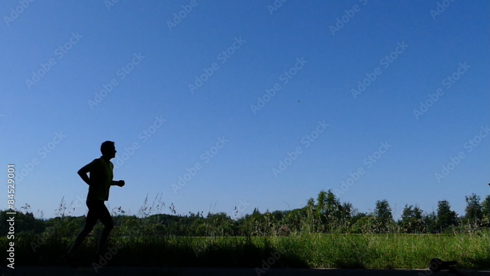 Jogger läuft als Silhouette vorbei, in Zeitlupe Jogger läuft als Silhouette vorbei, in Zeitlupe