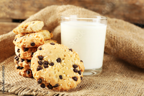 Tasty cookies and glass of milk on rustic wooden background