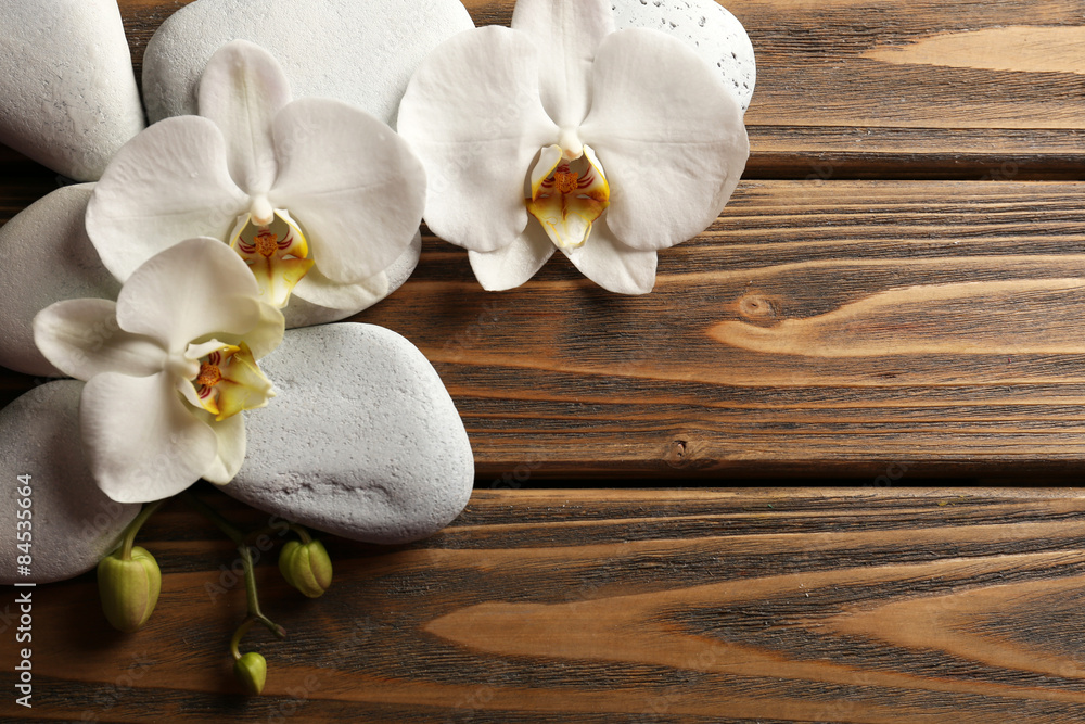Naklejka premium Spa stones and orchid flower on wooden background
