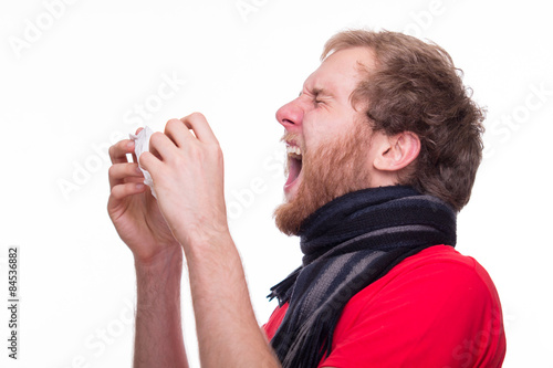 Man with runny noses neezes into a tissue photo