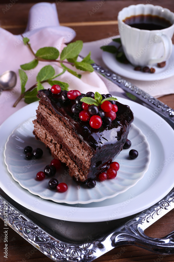Delicious chocolate cake with berries and cup of coffee on table close up Delicious chocolate cake with berries and cup of coffee on table close up