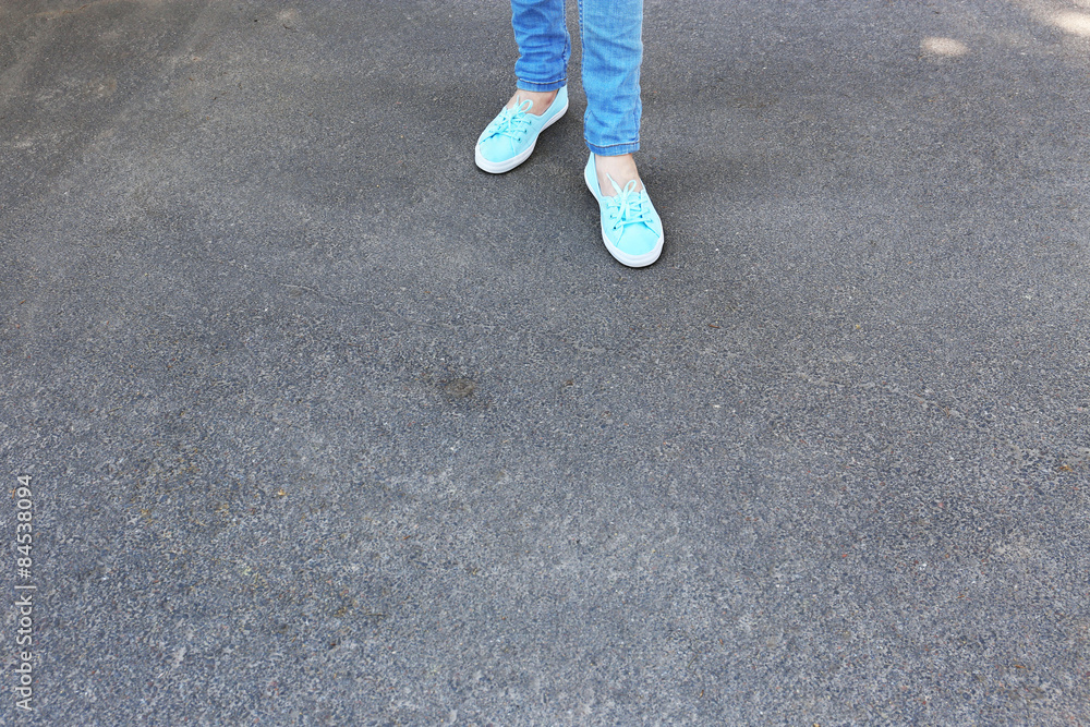 Female feet on gray asphalt background