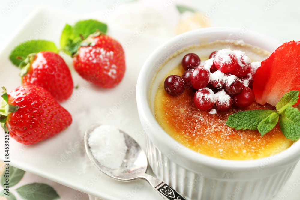 Creme brulee dessert with fresh strawberries and mint leaves, on color wooden background Creme brulee dessert with fresh strawberries and mint leaves, on color wooden background
