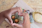 Vegetable salad wrapped into spring rolls with heart-shaped hand