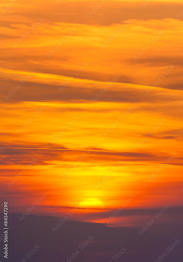 Obraz premium Jasny zachód słońca w ognistych chmurach cirrus - pionowy deseń natury
