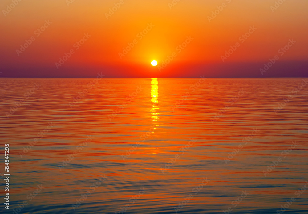 Bright sunset above tranquil sea surface with golden sun path