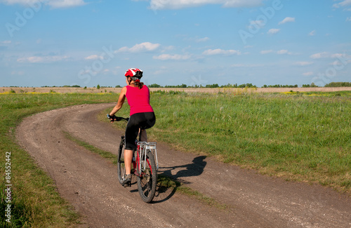 Young woman mountain bike ride on dirt road. Ukraine