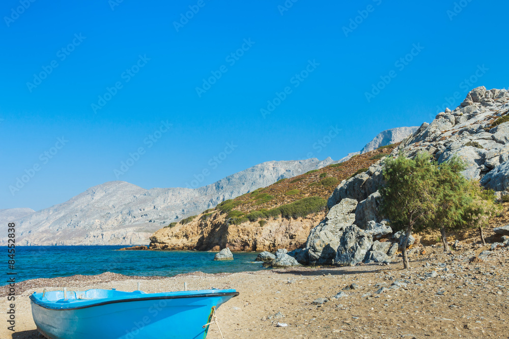 Blue fishermans boat and evergreen tamarisks on Alexi or Alexis beach near Emborios Greek village on Kalymnos island
