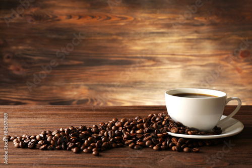 Cup of coffee with grains on wooden background