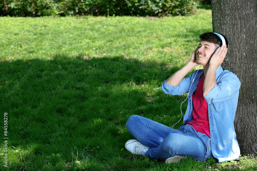 Man with headphones resting under tree in park Man with headphones resting under tree in park