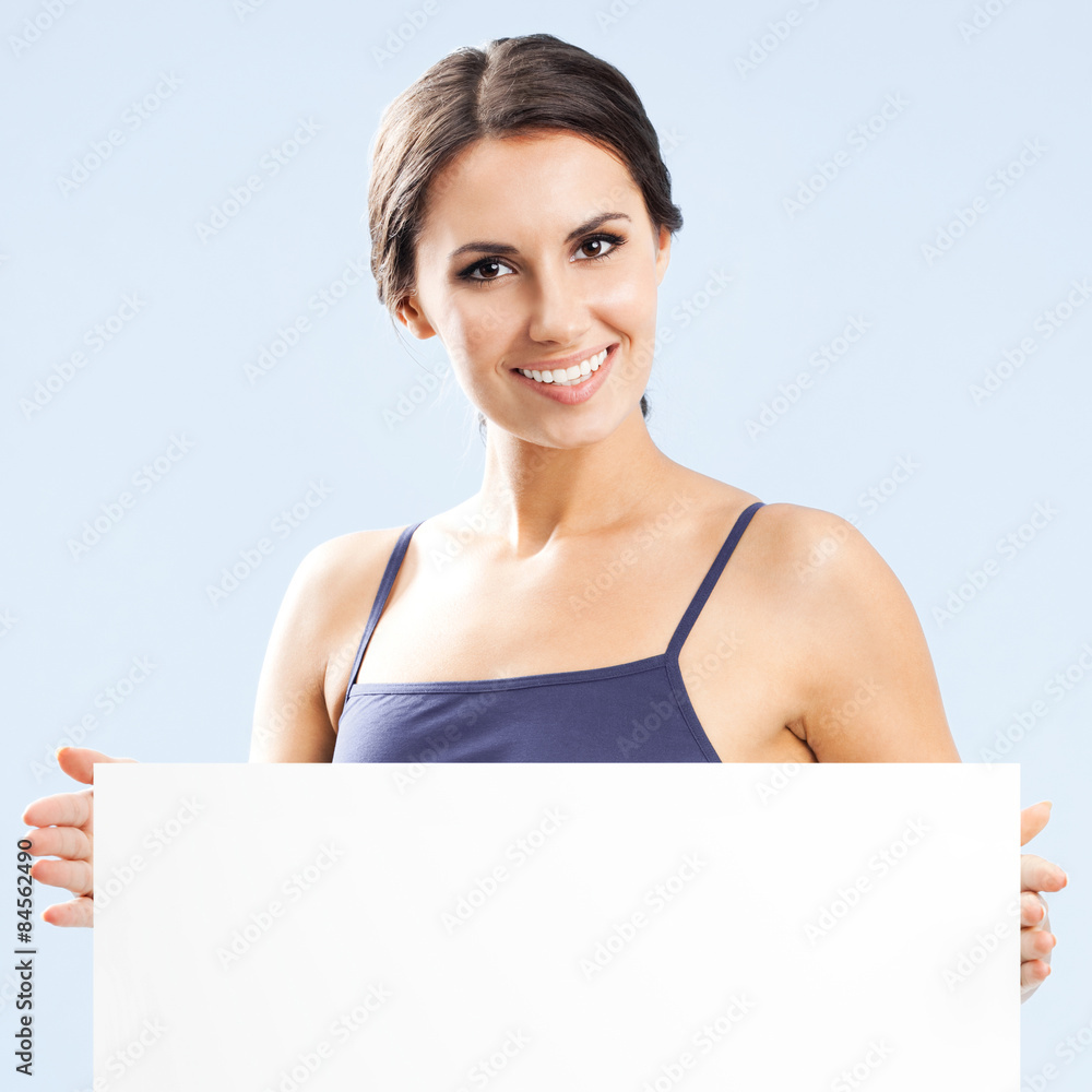 Woman in fitnesswear showing signboard, over grey Woman in fitnesswear showing signboard, over grey