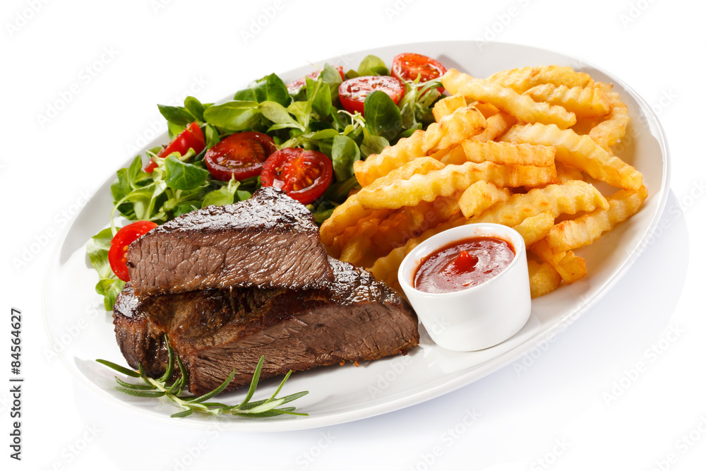 Grilled steak, French fries and vegetables on white background Grilled steak, French fries and vegetables on white background