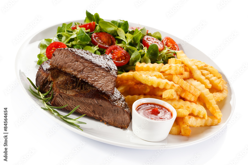 Grilled steak, French fries and vegetables on white background Grilled steak, French fries and vegetables on white background