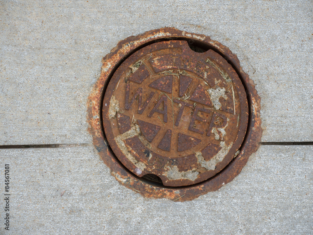 Rusty Iron cover provides access to a water main.