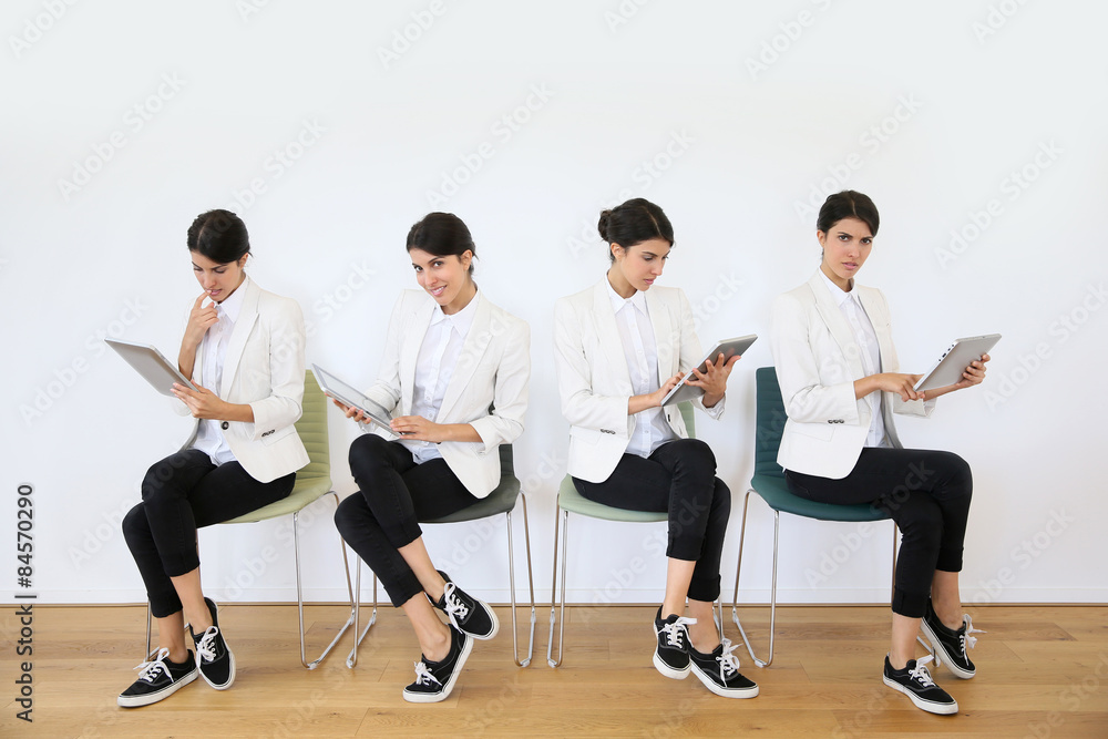 Women in waiting room using digital tablet