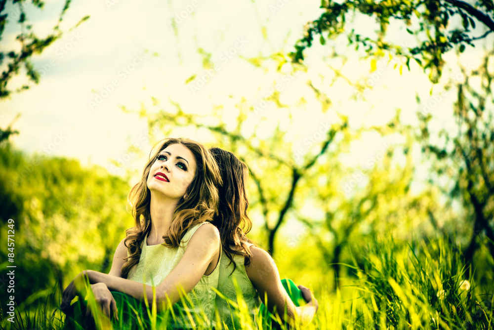 Two happy pretty girls sitting on the green grass Two happy pretty girls sitting on the green grass