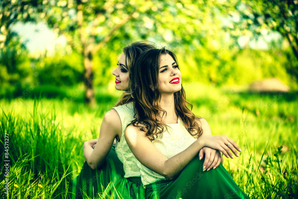 Two happy pretty girls sitting on the green grass Two happy pretty girls sitting on the green grass